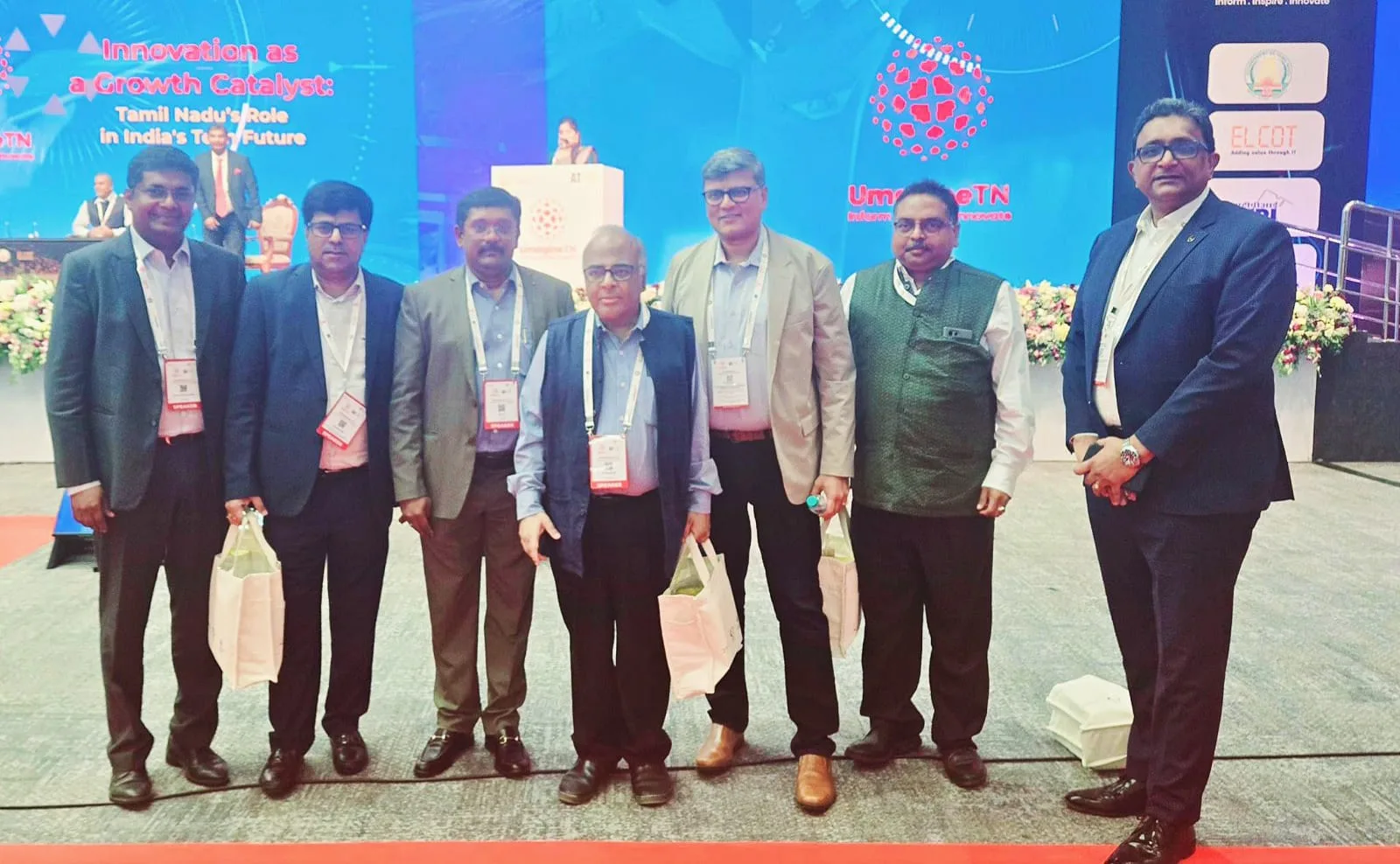Speakers photographed together at UmagineTN, beside a screen reading 'Innovation as a Growth Catalyst: Tamil Nadu's Role in India's Tech Future'.